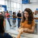 Mulher recebe cédulas no caixa de uma agência da Caixa com fila ao fundo
