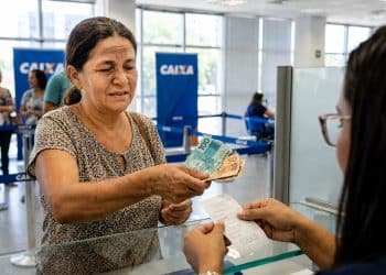 Mulher saca notas de R$ 100 e R$ 50 no caixa de uma agência da Caixa, em imagem que ilustra os pagamentos do Bolsa Família de junho, iniciados no dia 17 e mantidos até o dia 30