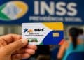 Cartão do BPC diante de agência do INSS, que paga R$ 1.621 ao beneficiário de final 3 nesta sexta (26)