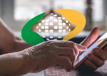 Idosa consulta a data de pagamento do BPC pelo celular, com a marca do INSS ao fundo
