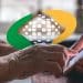 Idosa consulta a data de pagamento do BPC pelo celular, com a marca do INSS ao fundo