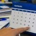 Pessoa aponta para um calendário de mesa de fevereiro que termina no dia 28, sem o dia 29 do ano bissexto