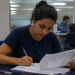 Mulher jovem preenche formulários sentada em mesa na Secretaria de Estado de Trabalho e Renda.