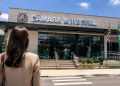 Pessoa em frente à Câmara Municipal representando divulgação de concurso público com vagas para níveis fundamental e médio.