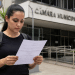 Candidata lê documento de concurso em frente à Câmara Municipal antes do fim das inscrições.