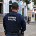 Guarda municipal visto de costas usando uniforme em área urbana.