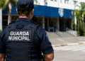 Guarda Municipal de costas em frente a prédio público durante atuação de vigilância urbana.