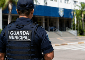 Guarda Municipal de costas em frente a prédio público durante atuação de vigilância urbana.