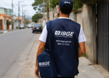 Agente do IBGE caminha por rua residencial com colete e bolsa institucional, representando atuação em campo no concurso para Agente Operacional.