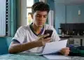 Estudante brasileiro segurando um documento e um celular em casa, representando o processo de confirmação da inscrição no Enem 2026 para candidatos isentos.