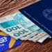 Carteira de Trabalho azul ao lado de cédulas de R$ 100 e cartão PIS/PASEP da Caixa, representando a consulta do Abono Salarial do quinto grupo