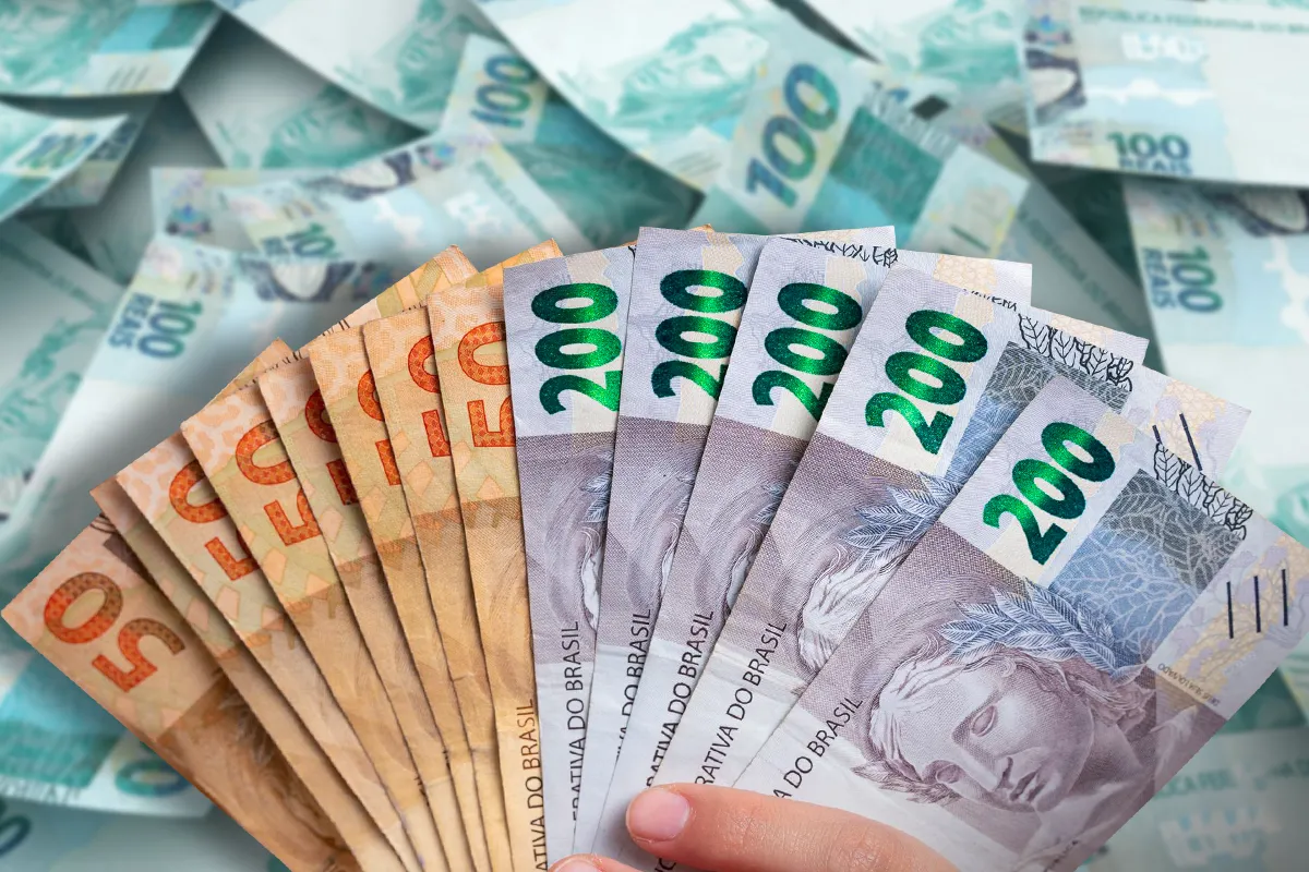 Leque de cédulas de R$ 50, R$ 100 e R$ 200 sobre fundo de notas, representando os valores a receber resgatados pelos brasileiros no SVR.