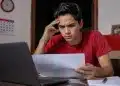Jovem estudante brasileiro concentrado em notebook, em ambiente doméstico simples, com expressão de atenção e preocupação, representando a inscrição no Enem 2026 antes do prazo final.