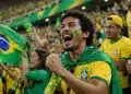 Torcedores brasileiros comemoram em arquibancada com camisas da seleção e bandeira do Brasil, representando o próximo jogo na Copa do Mundo.