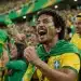 Torcedores brasileiros comemoram em arquibancada com camisas da seleção e bandeira do Brasil, representando o próximo jogo na Copa do Mundo.