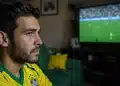 Jovem brasileiro assiste a jogo da Copa do Mundo na TV com expressão de cansaço visual.