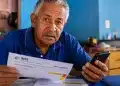 Idoso segurando extrato do INSS e celular em casa, com expressão de preocupação, representando os cuidados necessários para não perder o benefício do INSS.