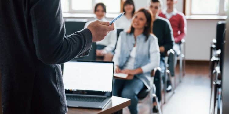 Instrutor de frente para turma de estudantes durante curso técnico em sala de aula