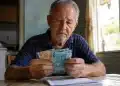 Idoso segurado do INSS segurando cédulas de dinheiro, representando o depósito de R$ 2.431,50 ou valor menor para esta terça-feira, 2 de junho.