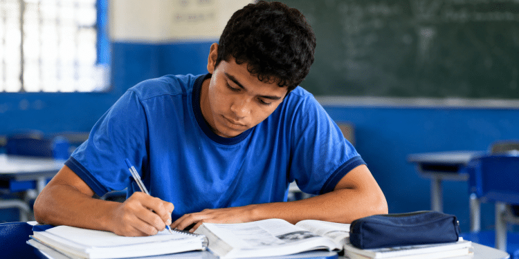 Estudante brasileiro escrevendo redação à mão durante estudo para o Enem em sala de aula.