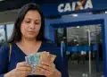 Mulher conferindo cédulas de dinheiro em frente à agência da Caixa, com dúvidas sobre a elegibilidade ao PIS/Pasep para quem recebe R$ 3.000.
