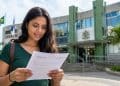 Mulher lê documento em frente a prédio público, representando as inscrições abertas do concurso da Câmara de Mauá
