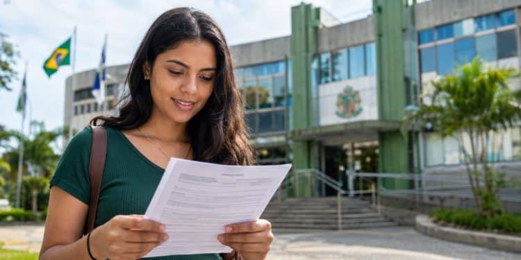 Mulher lê documento em frente a prédio público, representando as inscrições abertas do concurso da Câmara de Mauá