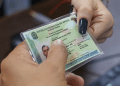 Mãos seguram a nova Carteira de Identidade Nacional plastificada com brasão da República e dados do portador
