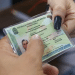 Mãos seguram a nova Carteira de Identidade Nacional plastificada com brasão da República e dados do portador.