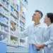 Farmacêuticos observam prateleiras de medicamentos, em imagem relacionada à importância da especialização para alcançar melhores cargos na carreira.