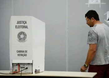 Eleitor diante de cabine de votação da Justiça Eleitoral em seção eleitoral