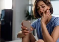 Mulher utilizando smartphone e demonstrando preocupação ao responder mensagens enquanto permanece conectada nas redes sociais.