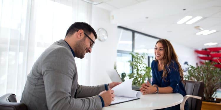 Recrutador analisa currículo diante da candidata, situação em que surgem as mentiras mais comuns em entrevistas de emprego