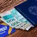 Carteira de trabalho azul com notas de 100 reais e cartão PIS/PASEP Caixa sobre mesa de madeira, simbolizando o pagamento de R$ 4.427 do PIS/Pasep.