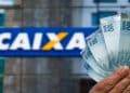 Notas de cem reais em frente à fachada da Caixa, banco que paga o Abono Salarial e o ressarcimento do PIS/Pasep.