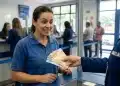 Mulher recebendo pagamento em agência bancária com expressão de surpresa, representando o pagamento do 13º salário antecipado para trabalhadores.