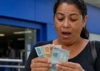 Mulher conferindo dinheiro em agência bancária, representando a confirmação do pagamento de quase R$ 4 mil liberado para CPF com final de 0 a 9.