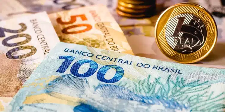 Notas de dinheiro em reais representando a liberação de pagamento do programa Pé-de-Meia em 1º de julho, com foco em benefício educacional.