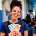 Mulher sorrindo, segurando cédulas de dinheiro em mãos, simbolizando as cinco regras para receber os R$ 1.050 do Pé-de-Meia Licenciaturas.