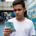 Estudante de uniforme branco observa cédulas de R$ 100 no pátio da escola, representando o incentivo do Pé-de-Meia para quem faz o Enem.