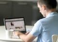 Homem sentado à mesa usa o laptop para acessar e atualizar o perfil no LinkedIn