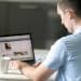 Homem sentado à mesa usa o laptop para acessar e atualizar o perfil no LinkedIn