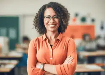 Professora sorrindo em sala de aula representando participantes da Prova Nacional Docente.