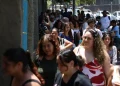 Fila de pessoas caminhando em ambiente urbano durante realização da Prova Nacional Docente.