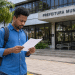 Homem lê documento em frente à Prefeitura Municipal durante processo seletivo para Agente Comunitário de Saúde.