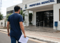 Candidato com documento de processo seletivo em frente à Prefeitura Municipal.