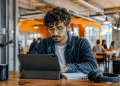 Jovem usando tablet em coworking moderno, representando preparação para profissões do futuro e novas tendências do mercado de trabalho.
