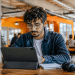 Jovem usando tablet em coworking moderno, representando preparação para profissões do futuro e novas tendências do mercado de trabalho.
