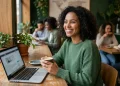 Mulher sorrindo trabalhando em laptop em café, simbolizando profissões flexíveis e renda extra.