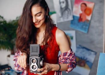 Mulher usa câmera analógica antiga, exemplo de profissões fora de moda que ainda remuneram bem